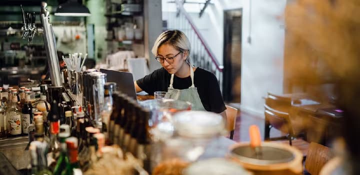 Young concentrating female bartender working at counter