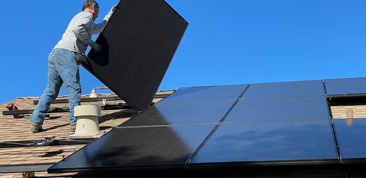 worker installing solar panels on a roof