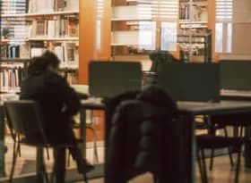 Student in the Library Reading Room Separated by a Glass from the Bookcases