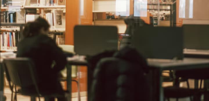 Student in the Library Reading Room Separated by a Glass from the Bookcases