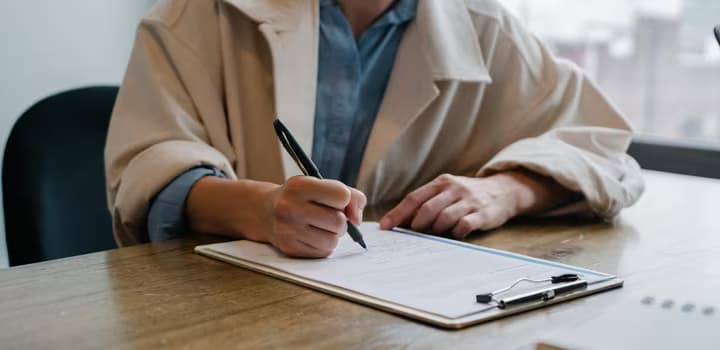Focused woman writing in clipboard while hiring candidate
