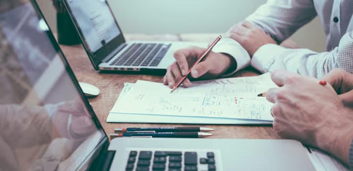 Person holding pencil near laptop computer