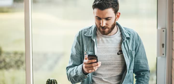Man holding a smartphone near the window